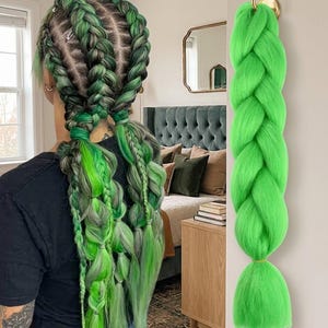 May include: A long, thick, single braid of vibrant lime green synthetic hair extensions hanging from a gold-colored wall hook. The hair is smooth, straight, and uniform in color, featuring a thick, three-strand plait design throughout.