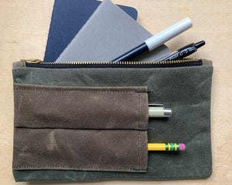 Estuche con cremallera de lona encerada, color verde oliva oscuro con compartimentos para bolígrafos marrones, edición limitada.