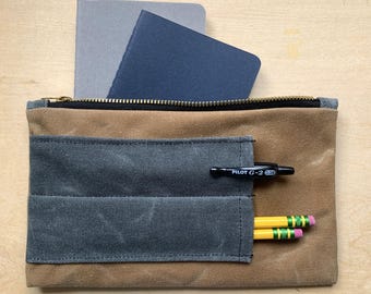 Estuche con cremallera de lona encerada, color arena con compartimentos grises para bolígrafos, edición limitada.