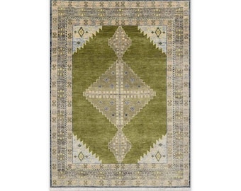 Peut inclure: Un tapis rectangulaire présentant un champ central vert olive uni avec un grand motif géométrique en losange au centre, dans des tons crème et bleu. Le tapis est encadré par une large bordure complexe grise, crème et bleue avec des franges.