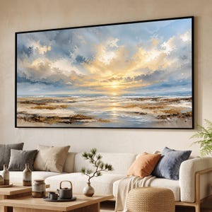 Puede incluir: Un gran cuadro de paisaje rectangular en un marco negro que representa una escena costera al atardecer. La obra presenta un sol dorado brillando a través de nubes texturizadas azules y blancas sobre una costa con tonos arena y agua azul.