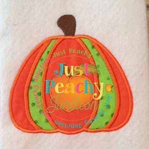 May include: An orange pumpkin applique with a brown stem and green accents. The pumpkin has the words "Just Peachy Junction" in a circular design. The center of the pumpkin has the words "Just Peachy" in colorful letters.