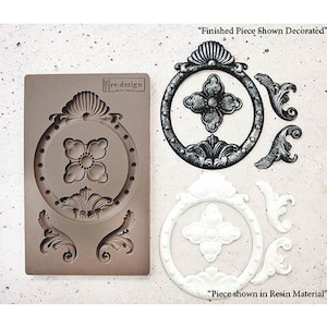 May include: A decorative mold with a floral design, a finished piece, and a resin piece. The mold is brown, and the finished piece is black and white. The resin piece is white. The text "Finished Piece Shown Decorated" and "Piece shown in Resin Material" are visible.