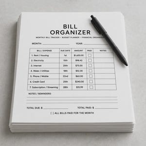 May include: A stack of white paper bill organiser sheets with black text and a black pen resting on top. The form includes columns for bill name, due date, amount, paid checkbox, and notes, with sections for monthly totals and reminders.