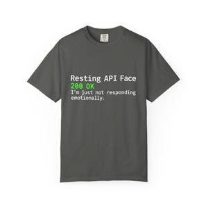 Op de afbeelding: Een donkergrijs t-shirt met korte mouwen en witte en groene tekst: Resting API Face, 200 OK, I'm just not responding emotionally. Het t-shirt heeft een ronde hals en een standaard pasvorm met een duidelijke grafische print op de voorzijde.