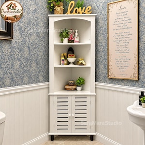 May include: A white corner cabinet featuring three open shelves and a lower storage compartment with two louvered doors. The unit has an arched top design and is positioned in a corner, holding various decorative items and small potted plants.