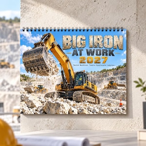May include: A 2027 wall calendar titled BIG IRON AT WORK featuring a yellow excavator lifting rocks in a quarry. The cover displays the text BIG IRON AT WORK 2027 Twelve Machines. Twelve Spectacular Jobsites. with other construction vehicles visible.