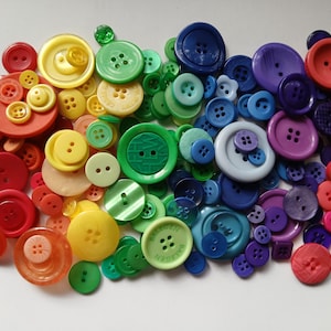 May include: A vibrant collection of colorful buttons arranged in a rainbow spectrum. The assortment includes various sizes and shades of red, orange, yellow, green, blue, and purple buttons, creating a visually appealing display.