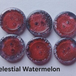 Puede incluir: Seis botones circulares dispuestos en dos filas de tres. Cada bot&oacute;n presenta un centro rojo intenso con una textura brillante y reluciente, rodeado por un borde oscuro y moteado con puntos blancos. El texto Celestial Watermelon est&aacute; debajo.