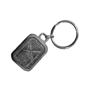 May include: Silver keychain with a rectangular tag featuring a stylized letter "A" design.