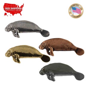 May include: Four pewter manatee figurines in different colors: silver, gold, copper, and gray. The figurines are all in the same pose, with their heads turned to the left and their tails curled up.