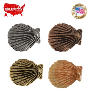 May include: Four scallop shell-shaped decorative accents in different finishes: silver, copper, gold, and natural. Each shell has a detailed, textured surface.