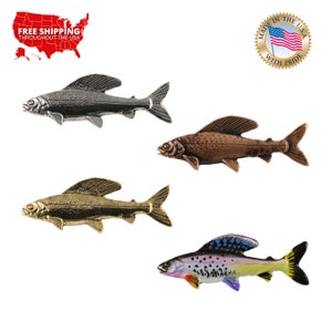 Puede incluir: Cuatro figuritas de peces de diferentes colores. Los peces están hechos de metal y tienen un diseño realista. Los peces son plateados, bronce, oro y multicolores.