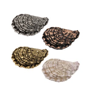 May include: Four oyster shell shaped decorative pieces in different finishes: silver, copper, gold, and white.