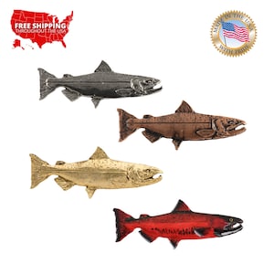 May include: Four metal salmon fish sculptures in different colors: silver, bronze, gold, and red. Each sculpture is detailed with fins, scales, and a realistic mouth.