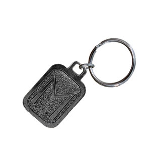 May include: Silver-toned keychain with a rectangular tag featuring a textured, raised letter "M". The keychain has a silver-toned ring.