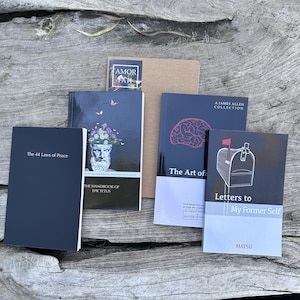 May include: A collection of five books with various cover designs. Titles include The 44 Laws of Peace, The Handbook of Epictetus, The Art of, Letters to My Former Self by Matsu, and a brown notebook labeled Amor Fati. The books feature black, white, and tan covers.