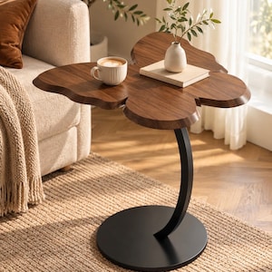 May include: A side table with a dark brown wood top shaped like a butterfly, supported by a curved black metal stem and a circular black base. A white ceramic mug and a small white vase on a book are placed on the table surface.