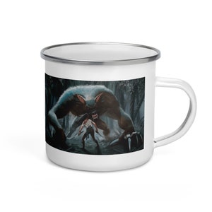 Może przedstawiać: Biały emaliowany kubek z ilustracją otaczającą wilkołaka atakującego osobę w lesie. Wilkołak jest szary i brązowy z ostrymi pazurami i zębami. Osoba trzyma dwa miecze. Kubek ma srebrną obręcz i biały uchwyt.