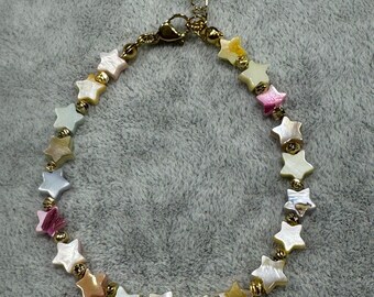 May include: A bracelet featuring a series of star-shaped beads in various iridescent pastel colours, interspersed with small gold-toned metallic spherical beads. The bracelet includes a gold-toned lobster claw clasp and an adjustable chain link extender.