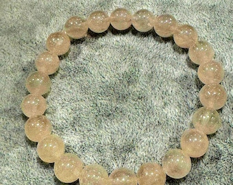 May include: A circular bracelet composed of twenty-two translucent, pale pink, spherical beads. Each bead features a smooth, polished surface with subtle internal inclusions, strung together to form a continuous, flexible loop.