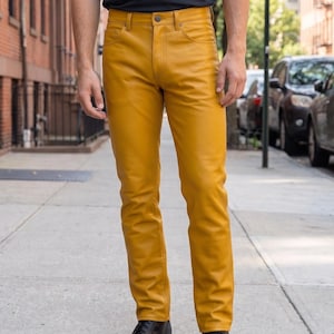 Könnte beinhalten: Senfgelbe Lederhose mit klassischem Fünf-Taschen-Design, Knopfverschluss und Reißverschluss. Die Hose hat einen geradlinigen Schnitt mit sichtbaren, farblich abgestimmten Nähten entlang der Taschen und des Bundes für eine strukturierte Optik.
