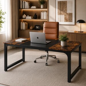 May include: A rectangular desk with a black metal frame and a surface featuring a mix of dark wood grain and solid black panels. A silver laptop sits on the center of the desk, accompanied by a small potted green plant and a closed white book.