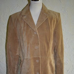 May include: A long, tan suede jacket with a button-up front and long sleeves.