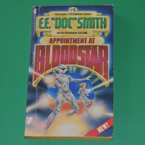 May include: A book cover with a yellow, red, and blue design. The title is "Appointment at Bloodstar" by E.E. "Doc" Smith with Stephen Goldin. The cover features a futuristic scene with a silver robot and a woman in a silver suit.