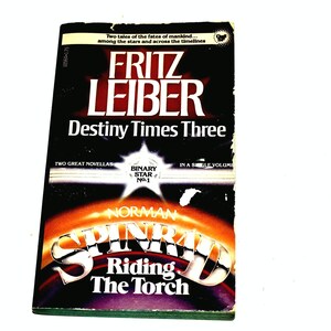 May include: A vintage paperback book titled "Destiny Times Three" by Fritz Leiber. The cover features a black background with red and white text. The book also includes the novella "Riding The Torch" by Norman Spinrad.