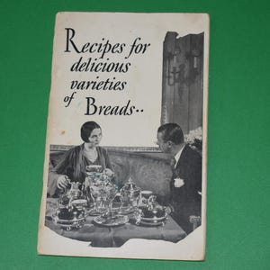 May include: Vintage cookbook cover with the title "Recipes for delicious varieties of Breads..". The cover features a black and white image of a man and woman seated at a table with a tea set.