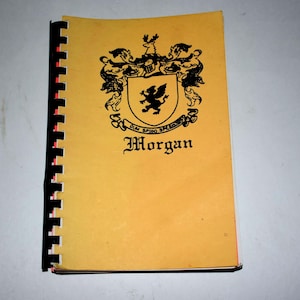 May include: A spiral-bound book with a yellow cover featuring a black crest and the name "Morgan" in a decorative font. The crest includes a shield with a griffin and the motto "Dum Spiro Spero".