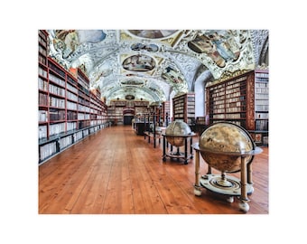 Op de afbeelding: Een bibliotheekinterieur met hoge houten boekenplanken langs de muren, een gepolijste houten vloer en een gewelfd plafond met beschilderde fresco's. Twee grote globes op houten standaards staan in het midden van het gangpad.