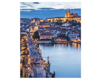 Op de afbeelding: Een hoog perspectief van de Karelsbrug in Praag tijdens de schemering, met stenen bogen, gloeiende straatlantaarns en wazige figuren die oversteken. Op de achtergrond weerspiegelt de Moldau de stadslichten en de Praagse Burcht.