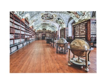 Op de afbeelding: Een historisch bibliotheekinterieur met hoge, donkerhouten boekenplanken vol boeken, een gepolijste houten vloer en een gewelfd plafond met versierde fresco's. Twee grote, antieke globes op houten standaards staan in het midden.