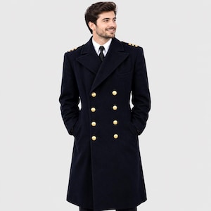 May include: A navy blue double-breasted overcoat featuring gold-toned buttons, wide lapels, and gold-colored shoulder epaulets. The coat is worn over a white collared shirt and a black necktie, extending to a knee-length hemline.