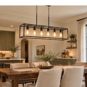 May include: A rectangular black metal frame chandelier featuring six exposed Edison-style light bulbs suspended by two chains. The fixture has a linear, open-cage design with a matte black finish, providing downward illumination over a dining area.