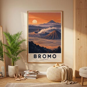 May include: A framed wall art print featuring a landscape illustration of Mount Bromo in Java, Indonesia. The artwork displays a volcanic crater with smoke, layered mountains, and a sunset sky. The text BROMO JAVA is printed in bold black letters.