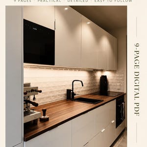 Peut inclure: Un guide PDF numérique de 9 pages intitulé Small One-Wall Kitchen Design Guide par Carolin Saser Studio. La couverture présente une photographie d'une cuisine avec des placards blancs, un plan de travail en bois foncé, un évier noir et un four noir.
