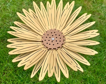 May include: A large, golden yellow metal sunflower with a brown center. The sunflower is made of many thin, overlapping petals and has a decorative design.