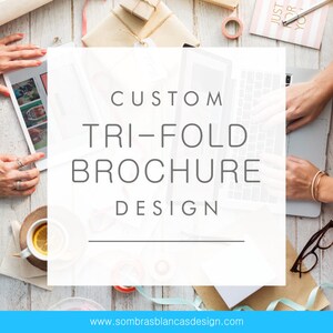 May include: A white text box on a wooden surface with the text "CUSTOM TRI-FOLD BROCHURE DESIGN" and the website address "www.sombrasblancasdesign.com".