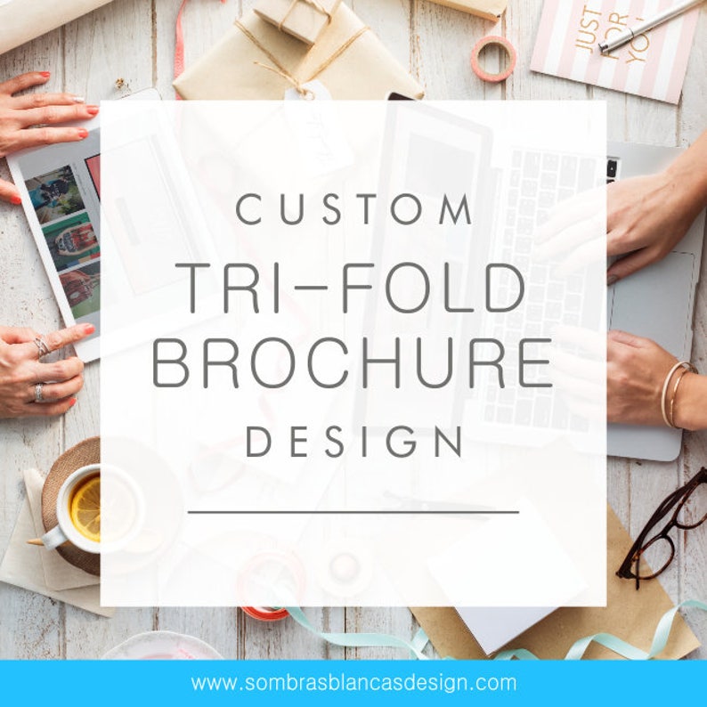 May include: A white text box on a wooden surface with the text "CUSTOM TRI-FOLD BROCHURE DESIGN" and the website address "www.sombrasblancasdesign.com".