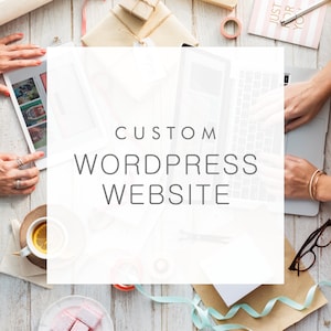 May include: A white background with the text "CUSTOM WORDPRESS WEBSITE" in gray text. The image also includes a laptop, a cup of tea, and other office supplies.