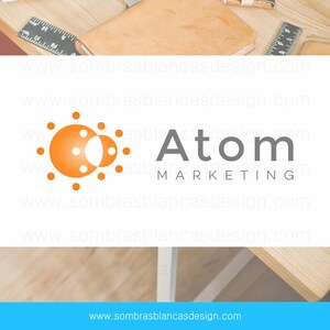 May include: A logo for Atom Marketing, a company that specializes in marketing. The logo features a stylized orange sun with a smaller orange circle inside. The text "Atom Marketing" is in gray below the sun.