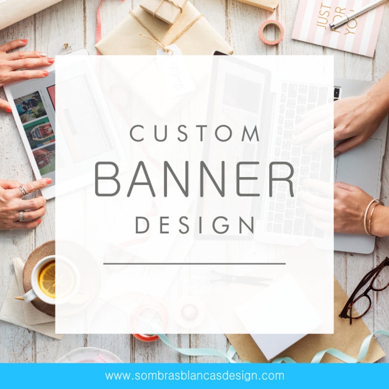 May include: A white laptop computer with the text "CUSTOM BANNER DESIGN" on the screen. The laptop is on a white wooden table with other office supplies, including a cup of tea, a notebook, and a roll of ribbon.