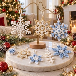 “Handmade crochet snowflake Christmas ornaments in white, cream, and light blue yarn, displayed hanging on an ornament stand and arranged on a marble surface with festive holiday decorations.”