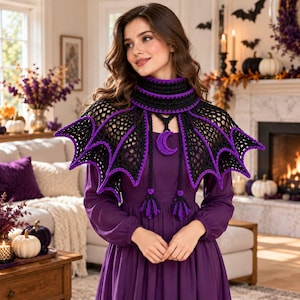 May include: A black and purple crocheted bat wing shawl featuring a high neck collar, a dangling crescent moon pendant, and two long braided ties with tasseled ends, worn over a solid purple long-sleeved dress.