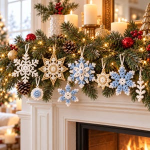 May include: A collection of crocheted snowflake ornaments in white, light blue, and gold hanging from a green pine garland. The ornaments feature intricate geometric patterns and loops for hanging, displayed alongside pinecones and warm string lights.