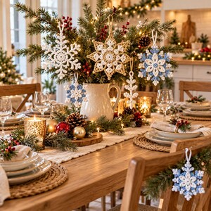 May include: A collection of crocheted snowflake ornaments in white, gold, and light blue hanging from a pine branch arrangement in a ceramic pitcher. The ornaments feature intricate geometric patterns and are displayed on a dining table.