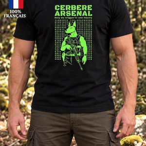 Peut inclure: Un t-shirt noir à manches courtes avec un motif vert vif représentant un canidé tenant un fusil. Le texte indique CERBERE ARSENAL et Only my trigger is non-binary, entouré de colonnes de chiffres en code binaire de couleur verte.
